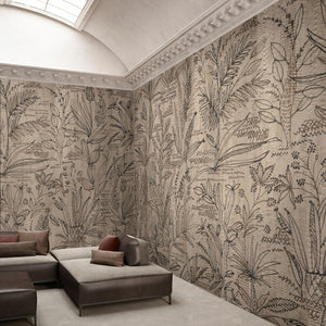 floral wallpaper on champagne colored background. Floral ornaments are black and in different shapes. There is a brown couch in the middle of the room with pillows. 