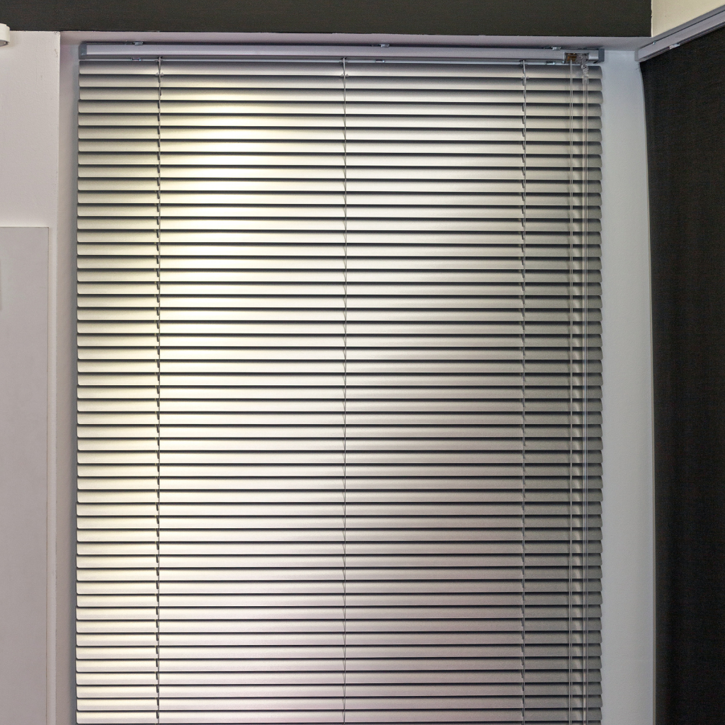photo of a window with white aluminum blinds. Blinds are closed.