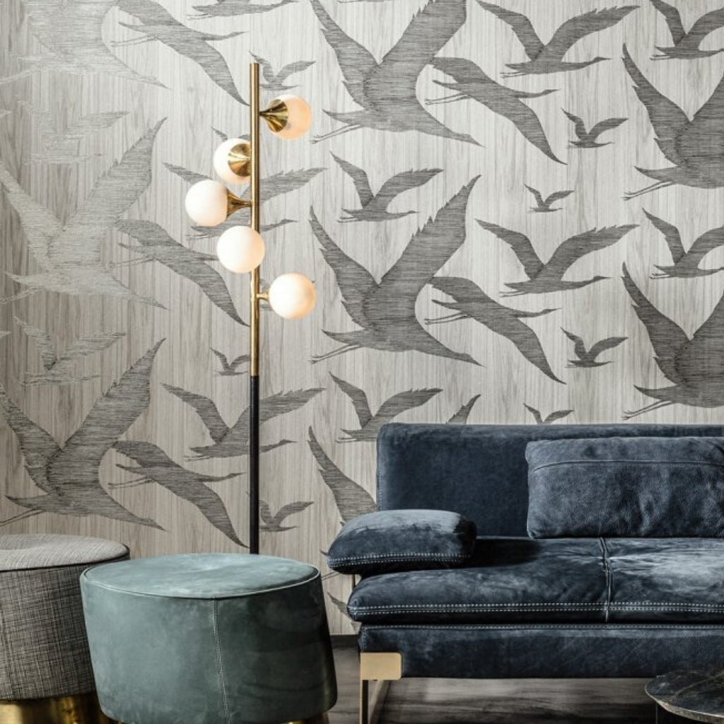 gray birds flying, wallpaper featuring birds. Velvet dark gray couch in front of the wall. 