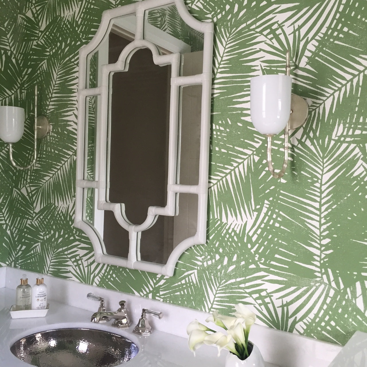 a photo of a bathroom with a metal sink, green bathroom wallpaper and white frame mirror