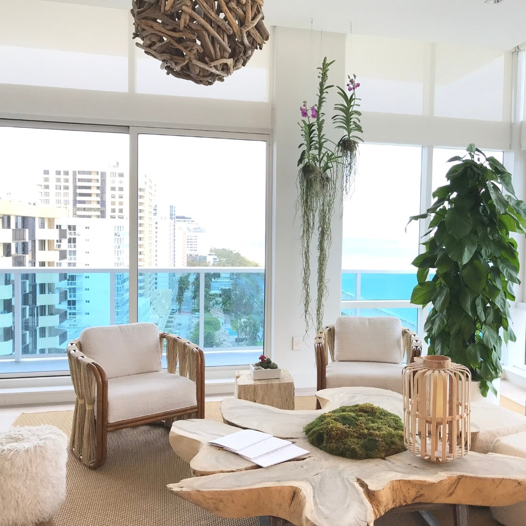 big window with a balcony. View to Miami Beach. Wooden chairs and table. Green plants and a lamp made of wooden sticks